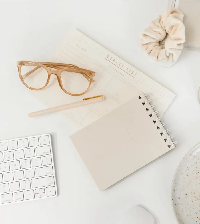 Helles Schreibtisch-Set mit Notizbuch, Brille und Stift – Symbol für Inspiration, Achtsamkeit und bewusste Planung der Feelgood Academy Events.